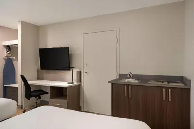 a room with a bed and a desk with a television at Days Inn by Wyndham Kelowna in Kelowna