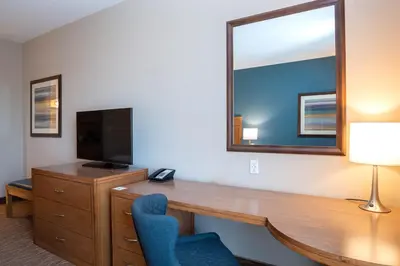a room with a desk with a television and a mirror at Sandman Hotel and Suites Squamish in Squamish