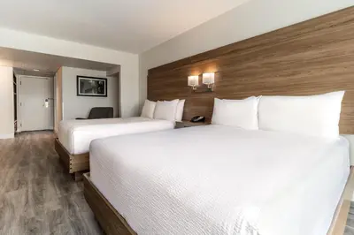 two beds in a hotel room with white sheets at Atrium Hotel Vancouver in Vancouver