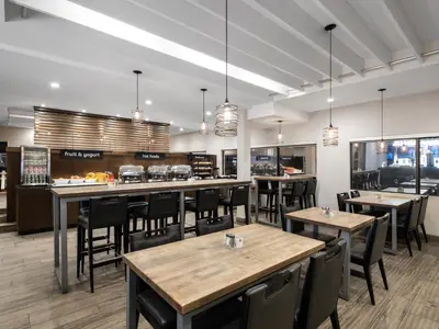 a restaurant with wooden tables and chairs and windows at Holiday Inn Calgary Airport by IHG in Calgary