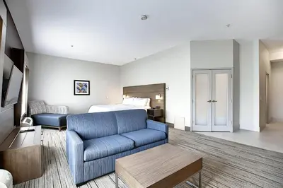 a hotel room with a couch and a bed at Holiday Inn Express Airport Calgary by IHG in Calgary