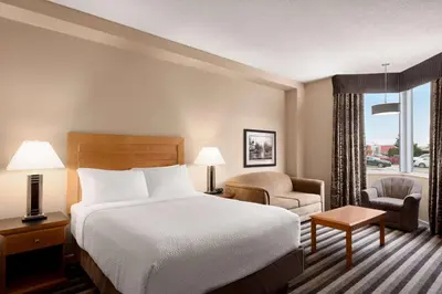a hotel room with a bed and a chair at Royal Hotel West Edmonton, Trademark Collection by Wyndham in Edmonton