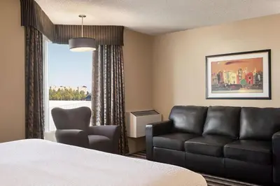 a hotel room with a bed and a couch and a window at Royal Hotel West Edmonton, Trademark Collection by Wyndham in Edmonton