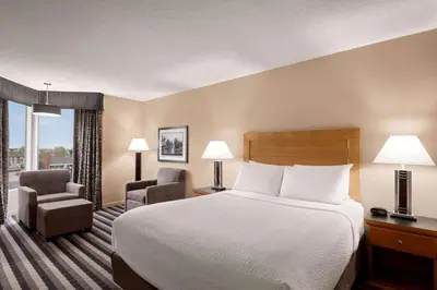 a hotel room with a bed and two chairs at Royal Hotel West Edmonton, Trademark Collection by Wyndham in Edmonton