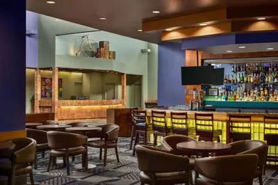 a bar in a restaurant with tables and chairs at Royal Hotel West Edmonton, Trademark Collection by Wyndham in Edmonton