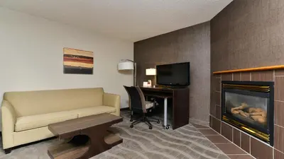 a hotel room with a couch and a desk and a fireplace at Holiday Inn Express Hotel & Suites - Edmonton International Airport by IHG in Nisku