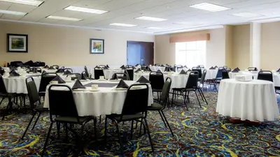 a room filled with tables and chairs with white tablecloths at Holiday Inn Express Hotel & Suites - Edmonton International Airport by IHG in Nisku