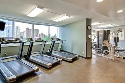 a gym with cardio machines and a large window at Chateau Lacombe Hotel in Edmonton