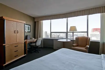 a hotel room with a bed and a desk and window at Chateau Lacombe Hotel in Edmonton