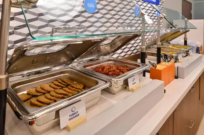 a buffet line with trays of food on a counter at Holiday Inn Express Hotel & Suites Sherwood Park-Edmonton Area by IHG in Sherwood Park