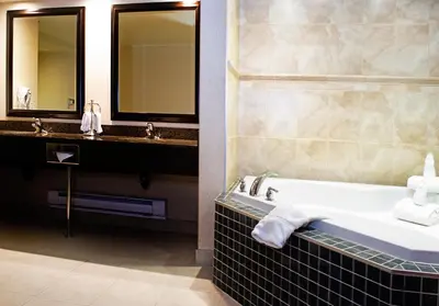 a bathroom with a tub and a sink and mirrors at Holiday Inn Hotel & Suites-West Edmonton by IHG in Edmonton