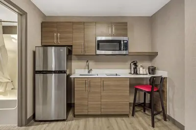 a kitchen with a stainless steel refrigerator and a red stool at Best Western Plus West Edmonton in Edmonton