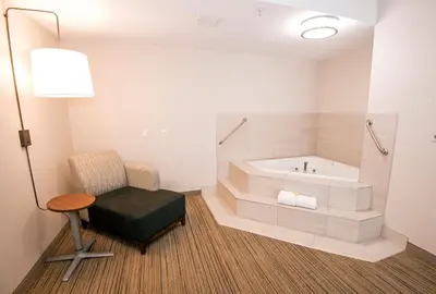 a bathroom with a tub and a chair and a table at Holiday Inn Express Hotel & Suites-Hinton by IHG in Hinton