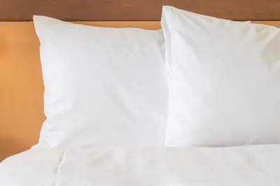 a stack of white pillows on a bed at Holiday Inn Express Hotel & Suites-Hinton by IHG in Hinton