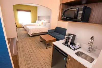 a small hotel room with a bed and a kitchen at Holiday Inn Express Hotel & Suites-Hinton by IHG in Hinton