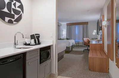 a hotel room with a bed and a kitchen with a sink at Holiday Inn Hotel and Suites-Kamloops by IHG in Kamloops