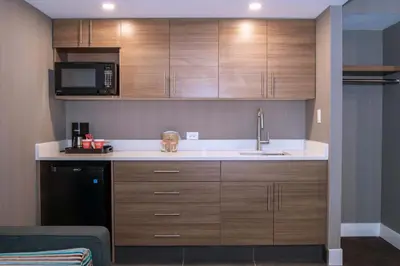 a kitchen with wooden cabinets and a sink and a microwave at Sandman Signature Calgary Downtown Hotel in Calgary