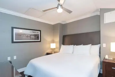 a bedroom with a large white bed with a ceiling fan at Sandman Hotel Vancouver Airport in Richmond