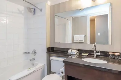 a bathroom with a sink and a toilet and a mirror at Sandman Hotel Vancouver Airport in Richmond