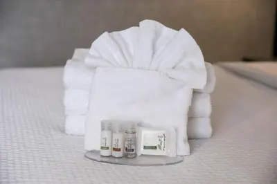 a pile of white towels and cosmetics on a bed at Days Inn by Wyndham Vancouver Airport in Richmond