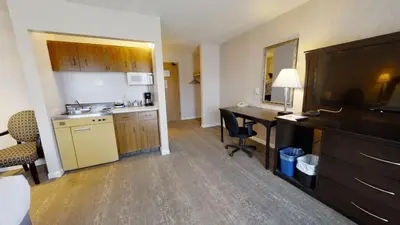 a hotel room with a kitchen and a desk with a computer at Dilworth Inn Kelowna in Kelowna