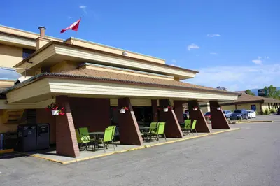 a building with green chairs in a parking lot at Dilworth Inn Kelowna in Kelowna