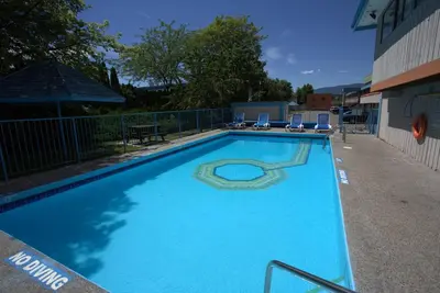 a large blue swimming pool with chairs and a fence at Recreation Inn and Suites Kelowna in Kelowna