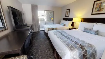 a hotel room with two beds and a television at Recreation Inn and Suites Kelowna in Kelowna