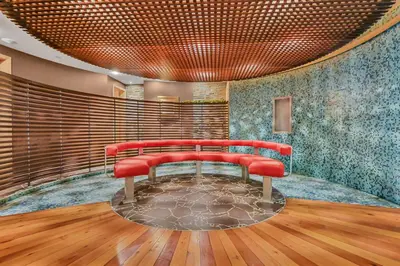 a red bench in a room with wooden floors at iHOTEL & Conference Centre Red Deer in Red Deer