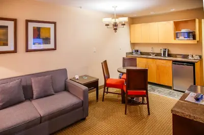 a living room with a couch and a kitchen at iHOTEL & Conference Centre Red Deer in Red Deer