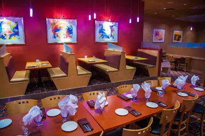 a restaurant with wooden tables and chairs and red walls at iHOTEL & Conference Centre Red Deer in Red Deer