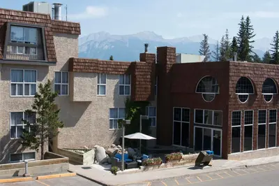 a large brick building with mountains in the background at Tonquin Inn in Jasper