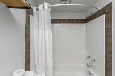 a bathroom with a shower with a white shower curtain at Tonquin Inn in Jasper