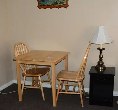 a wooden table with two chairs and a lamp at Bluebird Motel in Port Alberni