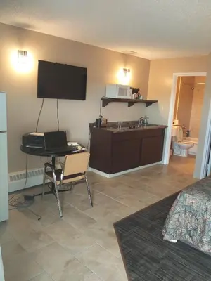 a room with a desk with a laptop and a television at Alaskan Motel in Fox Creek