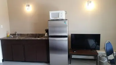 a kitchen with a refrigerator with a microwave on top of it at Alaskan Motel in Fox Creek