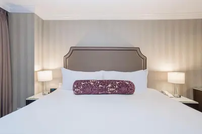 a bedroom with a large white bed with two lamps at La Grande Residence at the Sutton Place Hotel in Vancouver