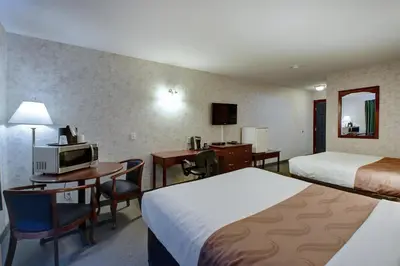 a hotel room with two beds and a desk at Ramada by Wyndham Nisku Edmonton Airport in Nisku