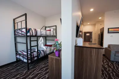 a room with two bunk beds and a desk at Encore Suites by Service Plus Inns in Grande Prairie