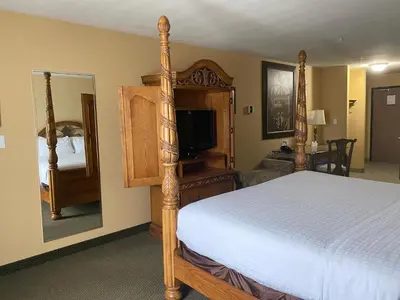 a bedroom with a canopy bed and a television at Merit Hotel & Suites in Fort McMurray