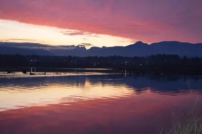 a sunset over a body of water with mountains in the background at Estuary House Reflexology B&B in Courtenay