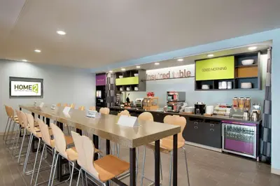 a restaurant with a long table and chairs and a counter at Home2 Suites by Hilton Fort St. John in Fort Saint John