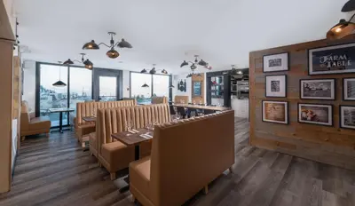 a dining room with a table and chairs and windows at Prestige Kamloops Hotel in Kamloops