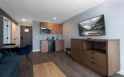 a living room with a couch and a kitchen at Prestige Kamloops Hotel in Kamloops