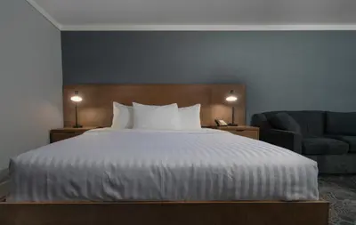 a bedroom with a large bed and a chair at Prestige Kamloops Hotel in Kamloops