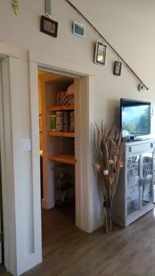 a living room with a tv and a shelf at Fish Tales Cottage in Port Renfrew
