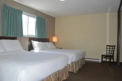 a hotel room with two beds and a chair at Siesta Suites in Kelowna