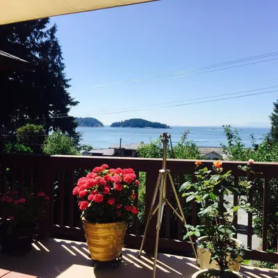 a balcony with flowers and a view of the water at Garden Bridge House in Sechelt