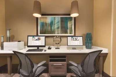 a computer desk with two monitors and two chairs at Homewood Suites by Hilton Calgary Downtown in Calgary