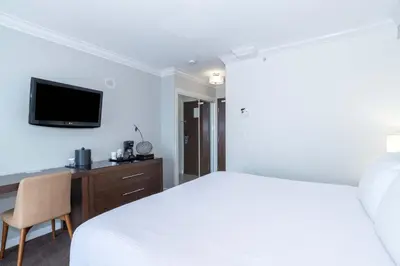 a bedroom with a white bed and a tv on the wall at Sandman Hotel & Suites Kelowna in Kelowna